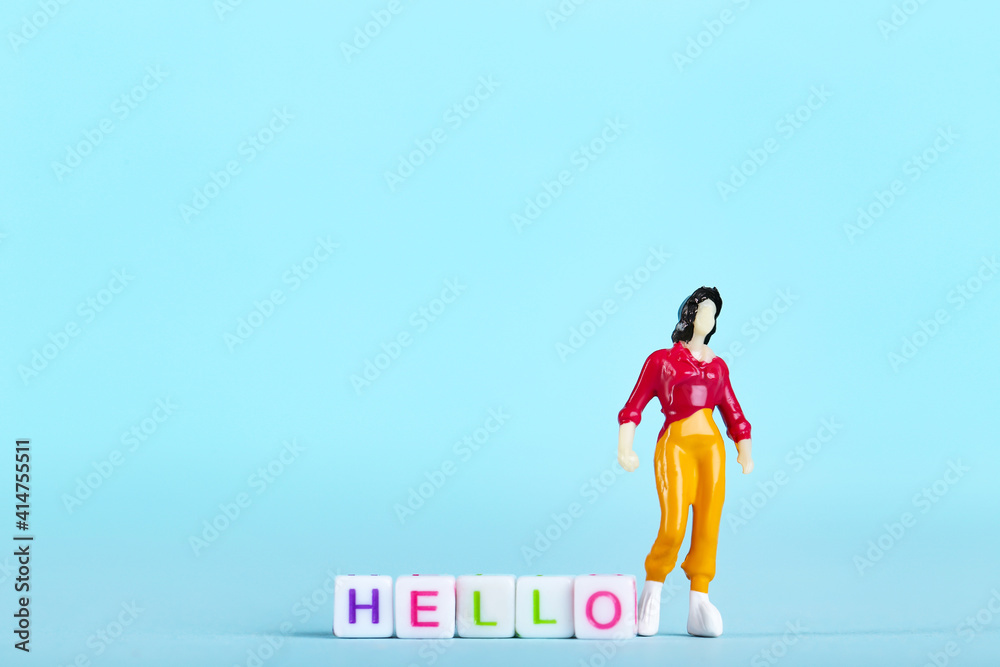 Miniature people and white cubes with text Hello on blue background