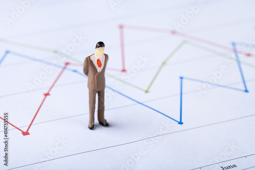 Miniature people and financial papers with graph and charts