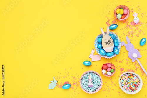 Easter concept. Sweet eggs with sprinkles and decorative rabbits on yellow background © 5second