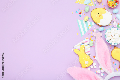 Easter gingerbread cookies with paper flags, rabbit ears, marshmallows and sprinkles on purple background photo