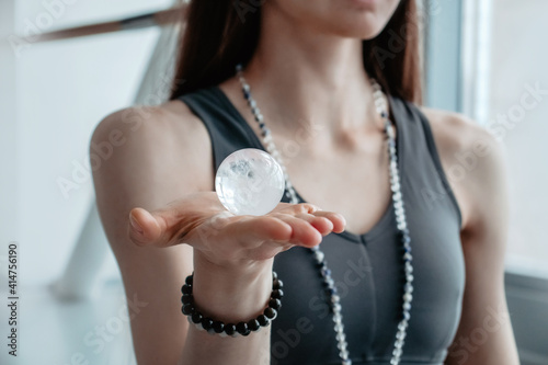 Woman in grey clothes holds in her hands semiprecious sphere , object for religious rituals, meditations and alternative medicine. Amazing mineral Ball