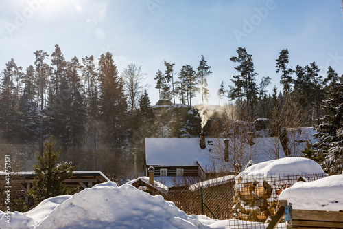 Winter village in the mountains, frosty sunny day, smoking from the chimneys of mountain cottages.