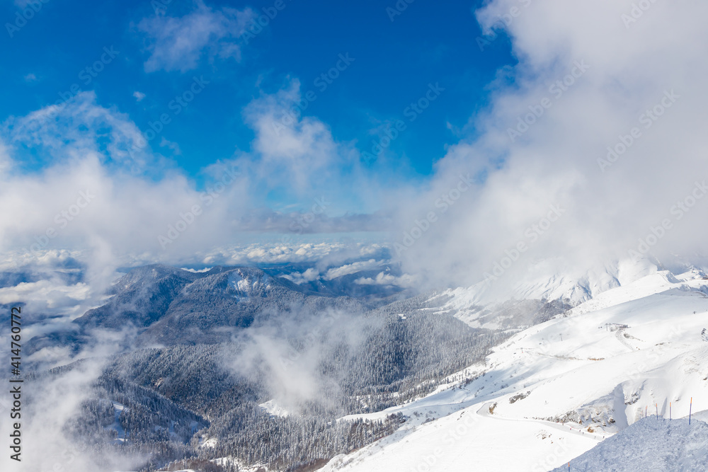 Beautiful snow landscape of snowy trees and ski slope of Roza Khutor ski resort. South part of mountains with sunny weather. Sochi, Russia.