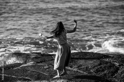 A young dance woman is engaged in choreography on the coast. Black and white photo.