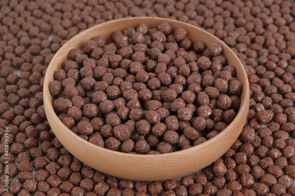 Chocolate corn balls in a wooden bowl scattered as a background texture. Top view. Copy, empty space for text Chocolate corn balls in a wooden bowl scattered as a background texture. Top view. Copy, empty space for text
