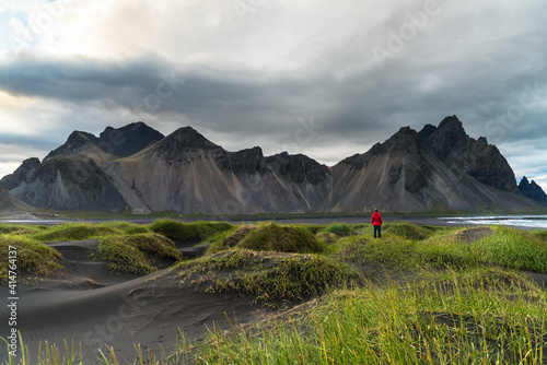 Dramatic volcanic landscape with sand dune in foreground in Iceland on a cloudy summer day. A lonely woman standing on a sand dune is admiring the beautiful scenery. © alpegor