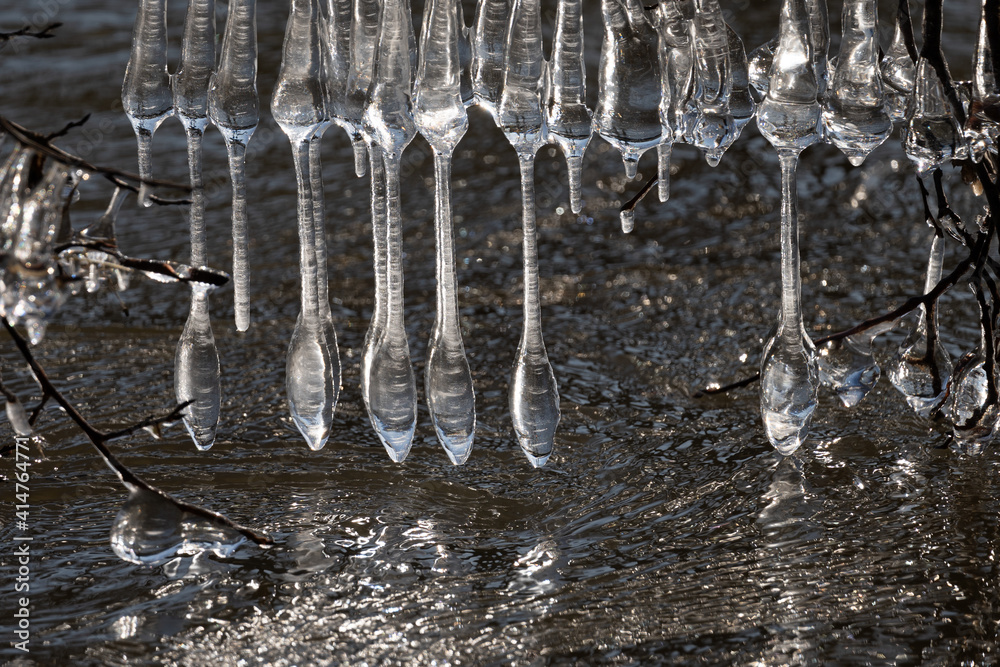 Light reflected through icicles at a river in winter time