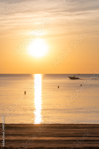 boat sailing at sunrise with the beach in the foreground