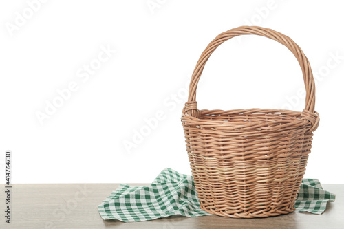 Foto Empty wicker basket and cloth on wooden table against white background, space for text