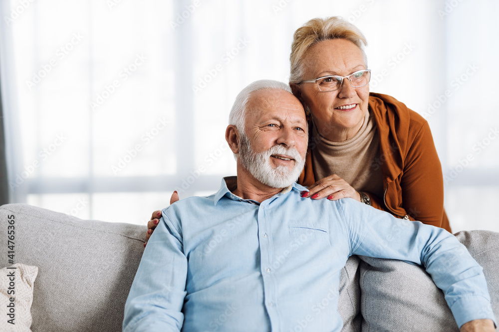 Happy senior couple relaxing together on a sofa at home Happy senior couple relaxing together on a sofa at home