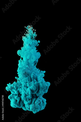 Ink dropped into the water and photographed while in motion. Paint swirling in water. Blue cloud and smoke of paint in water isolated on black background.