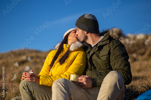 Happy couple sitting and kissing at the mountain. 