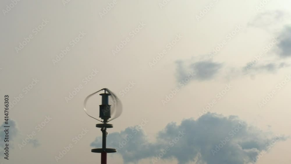 Vertical axis wind turbine utilize renewable wind energy while spinning against blue sky. Vertical axis wind turbine utilize renewable wind energy while spinning against blue sky.