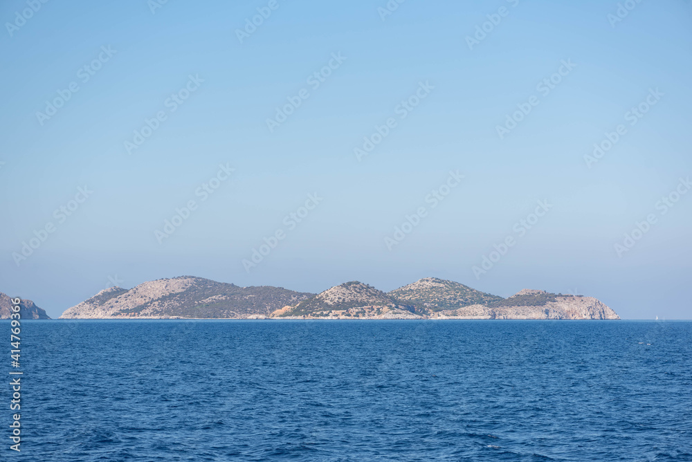 A mountainous island in the haze. The view of the sea from the sea.