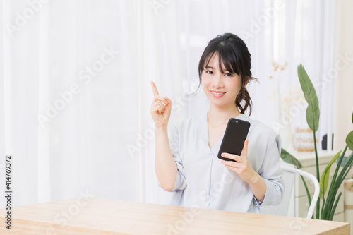 部屋でスマホを使う若い女性