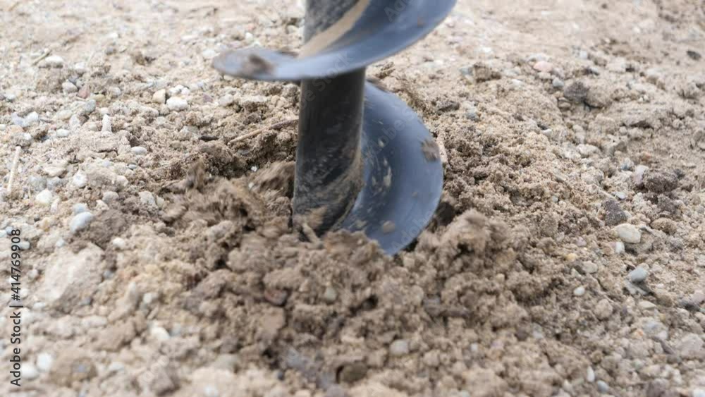 Slow motion view of hand held gasoline powered auger drill. The machine is used in the garden or on construction site for drilling holes in the ground. The soil is flying from blades of rotary parts. Slow motion view of hand held gasoline powered auger drill. The machine is used in the garden or on construction site for drilling holes in the ground. The soil is flying from blades of rotary parts.