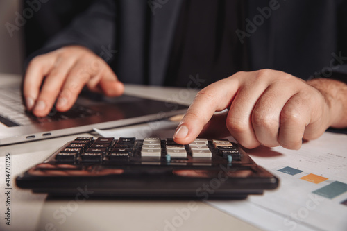 Man working in office using calculator. Business concept. Close-up.