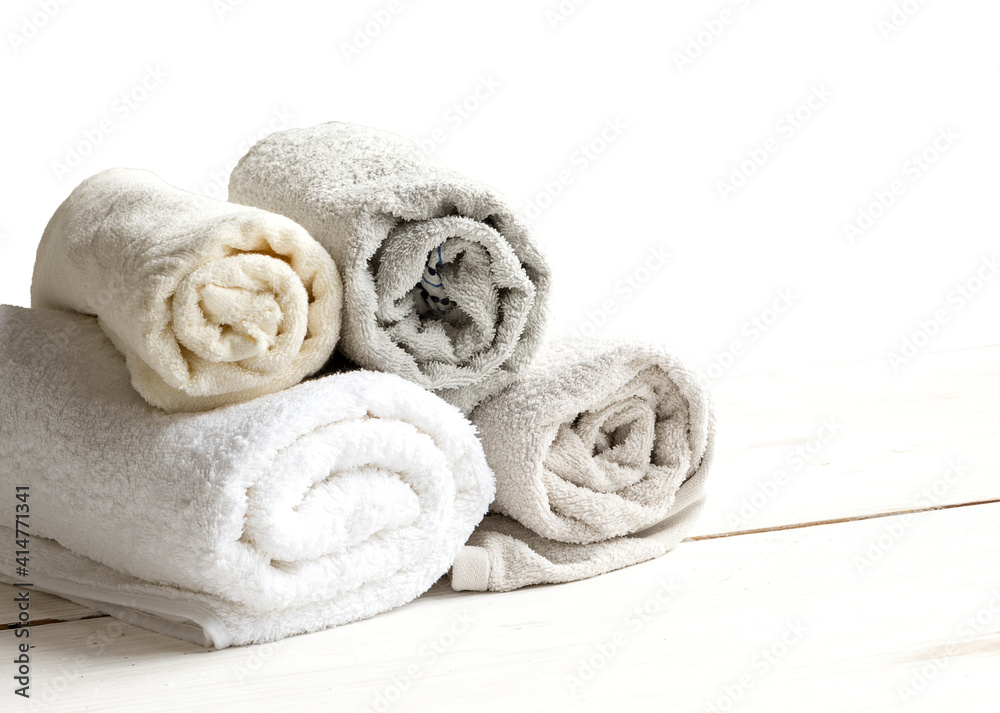 Close-up of light terry towels on a wooden table. Stack of textile bath towels isolated on white background Close-up of light terry towels on a wooden table. Stack of textile bath towels isolated on white background