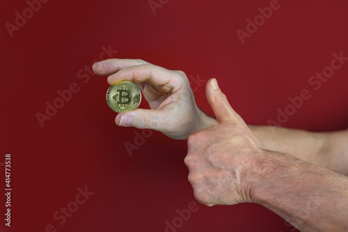 male hand hold coin gold bitcoin on red background, sale charts, up and down concept, banking, saving money, payments, e-business