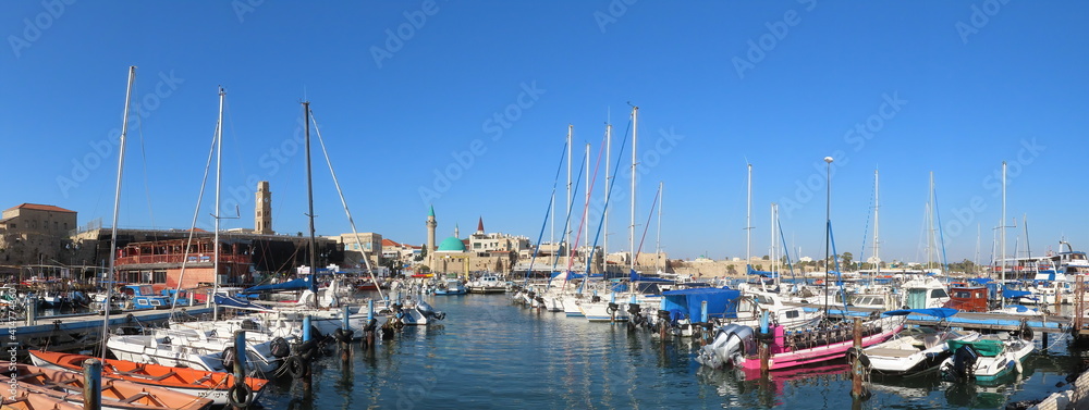 Acre, Israel - February 14, 2021. Beautiful panoramic views of the yachts at the pier and ancient architecture in the old city of Acre. Buildings of Muslim and Christian religions in one place. 