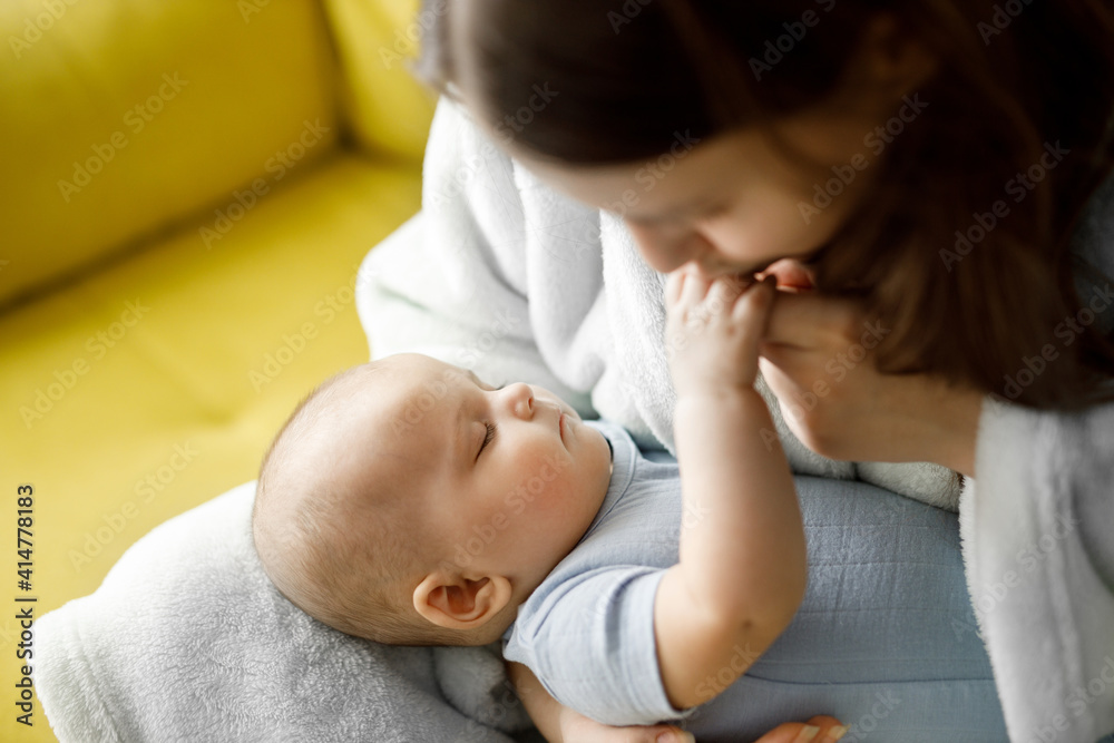 Loving mom carying of her newborn baby at home over window lighting. Woman holds and hugs her child. Bright portrait of happy mum holding sleeping infant child on hands. Loving mom carying of her newborn baby at home over window lighting. Woman holds and hugs her child. Bright portrait of happy mum holding sleeping infant child on hands.