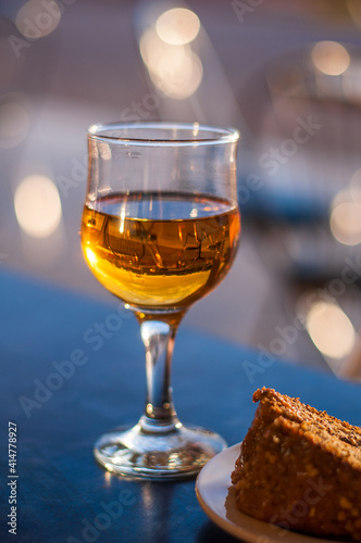 A glass of white dessert wine and a carrot pie on the table in a cafe