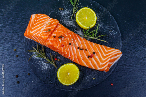 Raw salmon fillet with spices on black slate. Top view