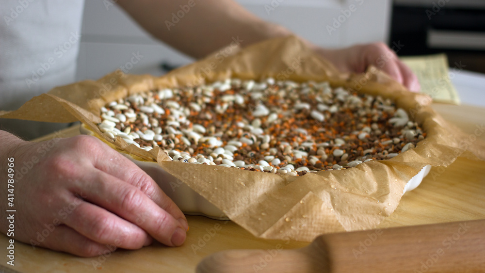 The process of making a base for a shortcrust quiche pie, male hands transfer a rolled dough sheet into a baking dish. Authentic home hobby home baker. Pie crust recipe