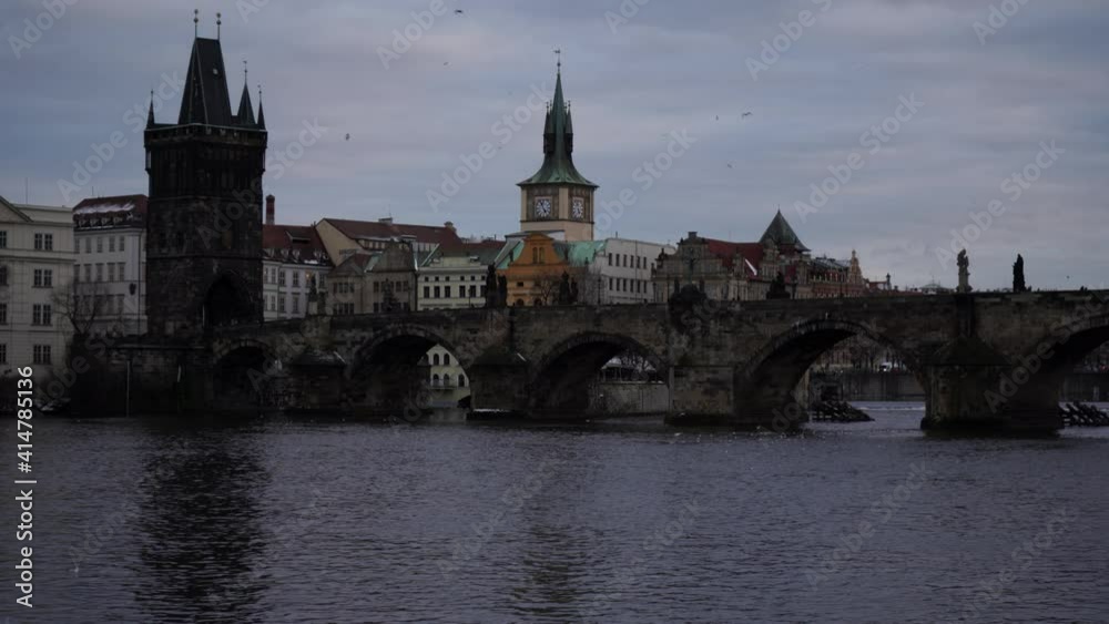 static view of Charles Bridge on the flowing river Vltava. people walk on the bridge. in the center of Prague in winter static view of Charles Bridge on the flowing river Vltava. people walk on the bridge. in the center of Prague in winter