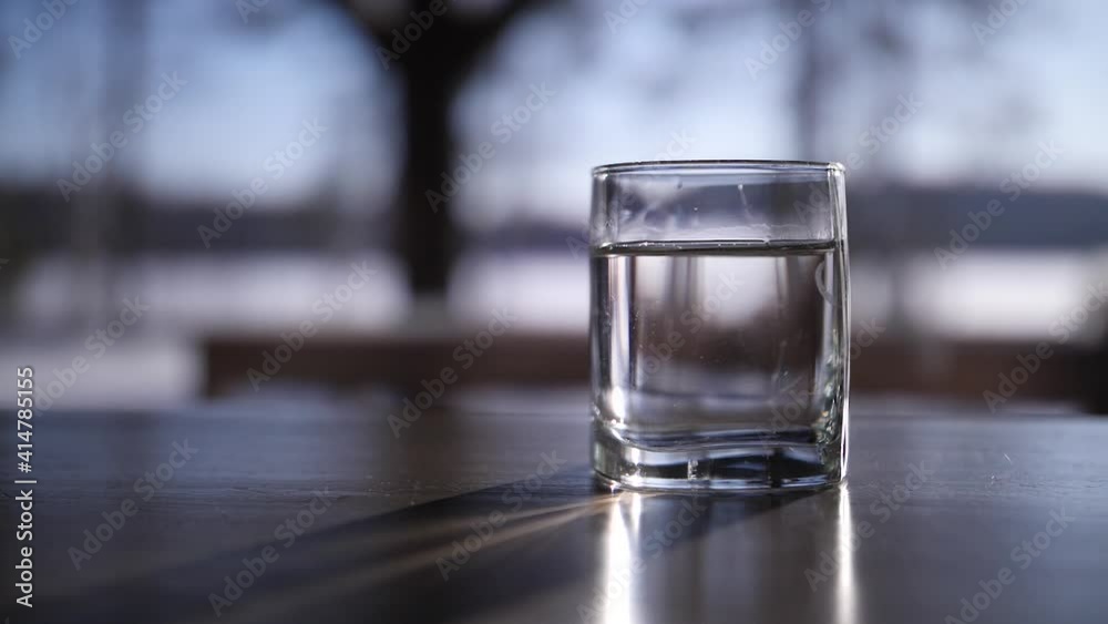 a man puts a glass of water on the table a man puts a glass of water on the table