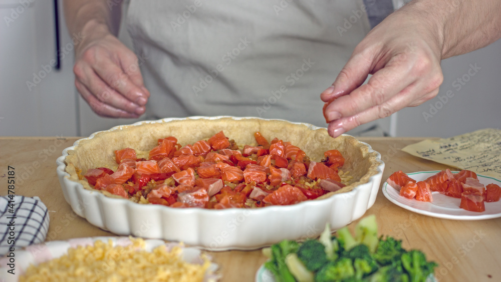 A man in the kitchen bakes a fish pie quiche close-up