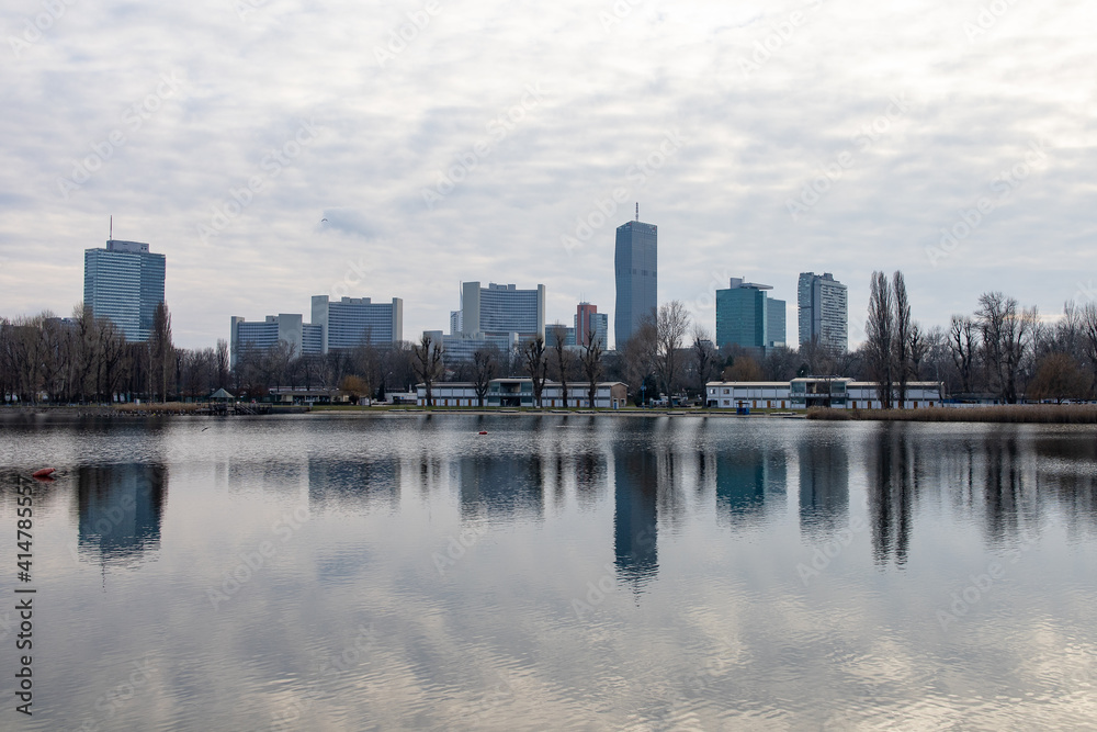 Skyline of VIC (UNO city) in Vienna, Austria as seen from across Alte Donau (Old Danube) in winter, with reflections of the buildings on the water.