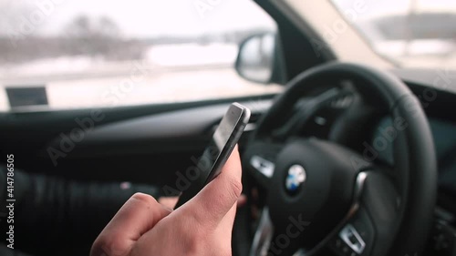 Wallpaper Mural The man's hand uses the phone in his hand while driving a car. Communication while driving on the road. Use of mobile internet. Driver multitasking. Torontodigital.ca