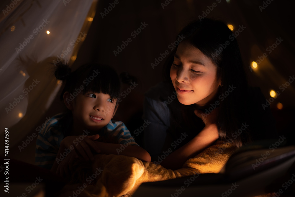 Little girl looking and reading a homework on the book at home with her mother, She has her head on her hand and her mother is explaining something, night shot with cozy warm light, mother teaching Little girl looking and reading a homework on the book at home with her mother, She has her head on her hand and her mother is explaining something, night shot with cozy warm light, mother teaching