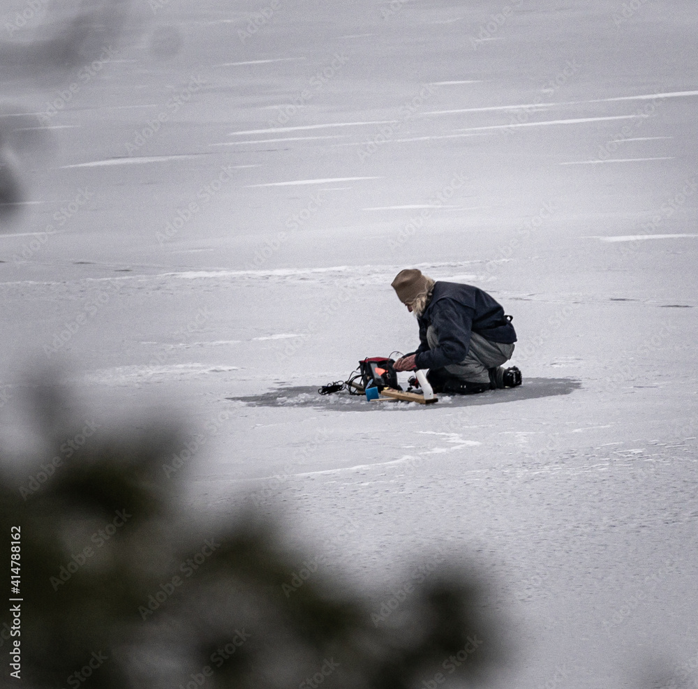 A guy preps the ice for ice fishing on the Otsego lake in Cooperstown, New York.