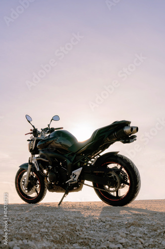 amazing sport black motorcycle parked with pink sunset sky