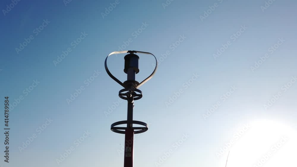 Vertical axis wind turbine utilize renewable wind energy while spinning against blue sky. Vertical axis wind turbine utilize renewable wind energy while spinning against blue sky.