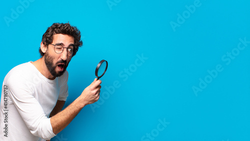 young crazy bearded man looking and trying to find with a magnifying glass