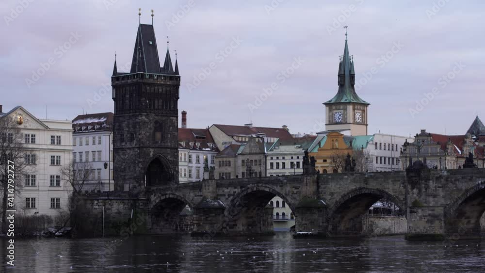 Charles Bridge on the flowing river Vltava. people walk on the bridge. in the center of Prague in winter Charles Bridge on the flowing river Vltava. people walk on the bridge. in the center of Prague in winter
