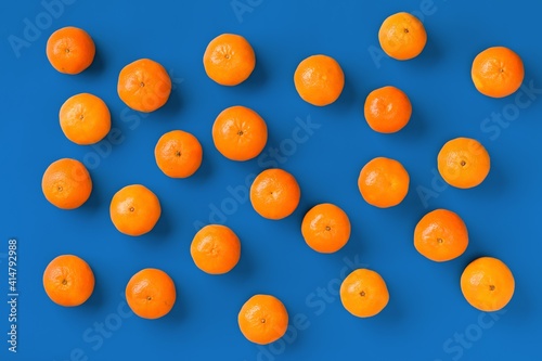Fruit pattern of fresh orange tangerine or mandarin on blue background. Flat lay, top view. Pop art design, creative summer concept. Citrus in minimal style. © Natika