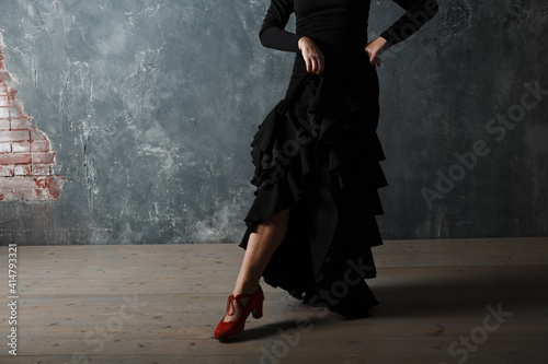 Young adult spanish woman dancing flamenco on grey vintage background
