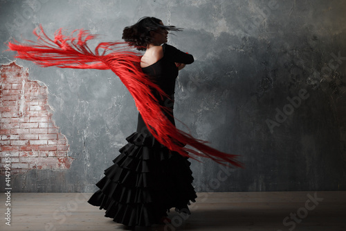 Young adult spanish woman dancing flamenco on gray vintage background