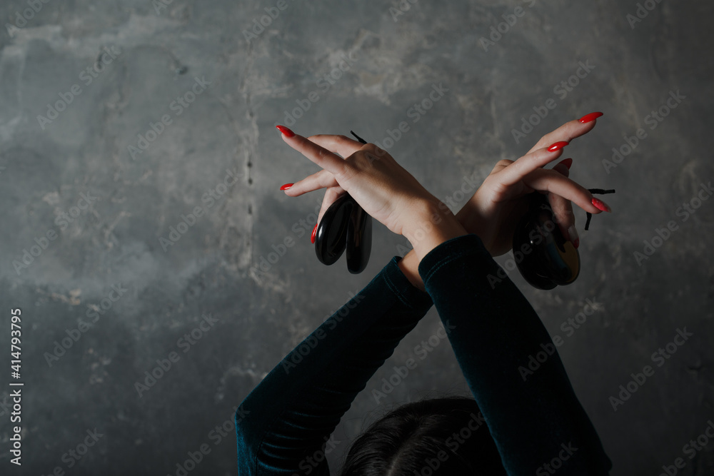 Obraz premium Young adult spanish woman dancing flamenco with castanets on gray vintage background