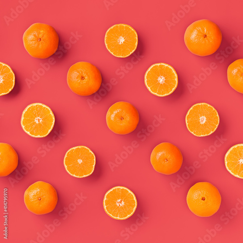 Fruit pattern of fresh orange tangerine or mandarin on living coral background. Flat lay, top view. Pop art design, creative summer concept. Citrus in minimal style.