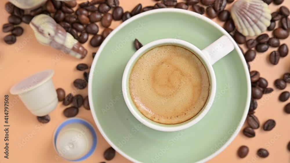 Coffee break. A cup of aromatic espresso coffee with froth. Traditional Italian breakfast drink on a bright background with capsules and coffee beans. FullHD footage Coffee break. A cup of aromatic espresso coffee with froth. Traditional Italian breakfast drink on a bright background with capsules and coffee beans. FullHD footage
