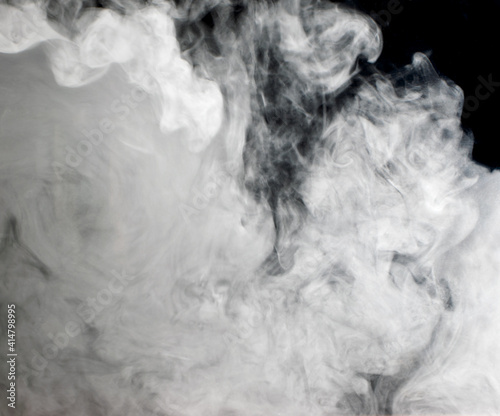 Abstract background of chaotically mixing clouds of white smoke against a background of darkness