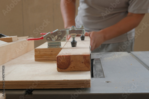 Quadro em tela Selective focus picture of jig holding wood while trimming on saw table