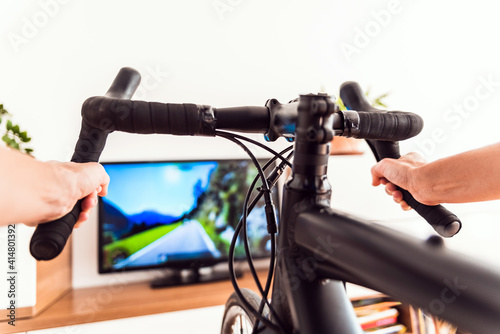 Cycling Indoor with exercise bike trainer motivating himself with the gamification of sport.