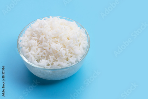 Glass bowl of rice on blue background.