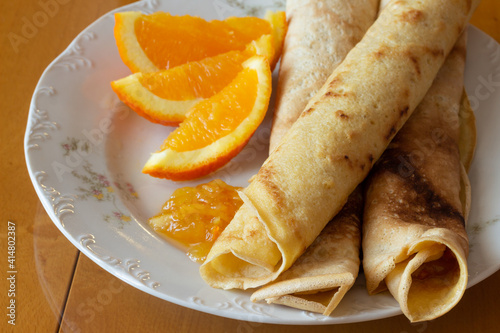 Crepes with orange jam and oranges  - wooden background